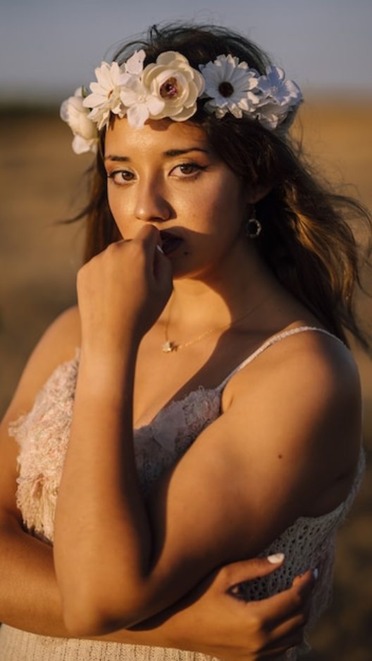 Mulher usando brinco floral grande e colar aromático ao mesmo tempo, em uma rua de Ipanema ao fim da tarde. Estilo próprio é mistura, ousadia e muito bom humor, do jeito que a Órbita gosta.